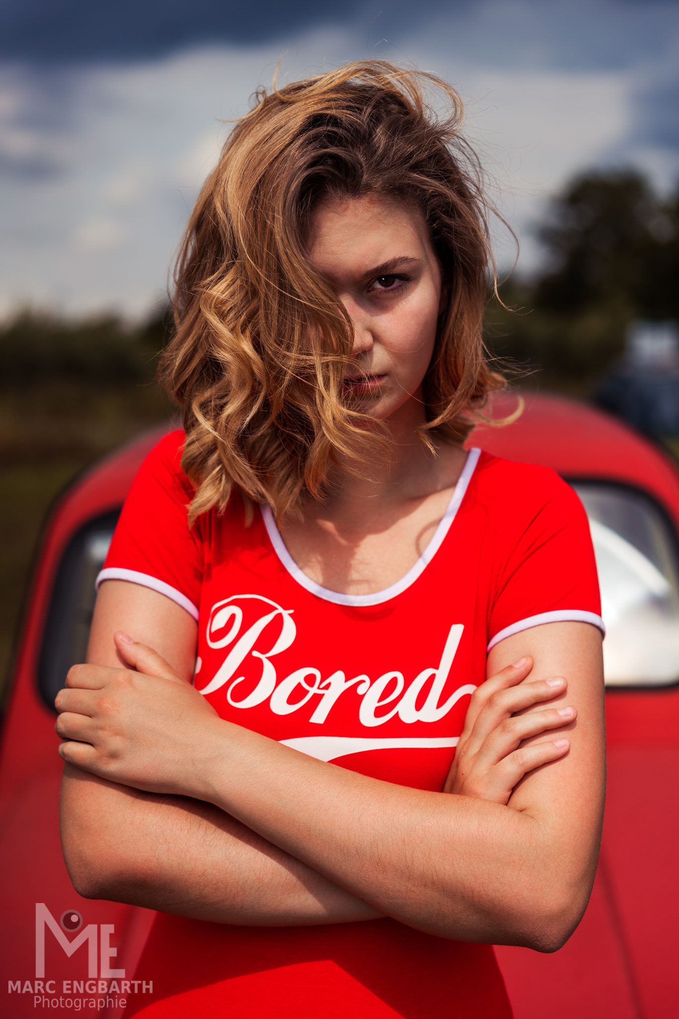 Frau im roten Shirt lehnt am Auto